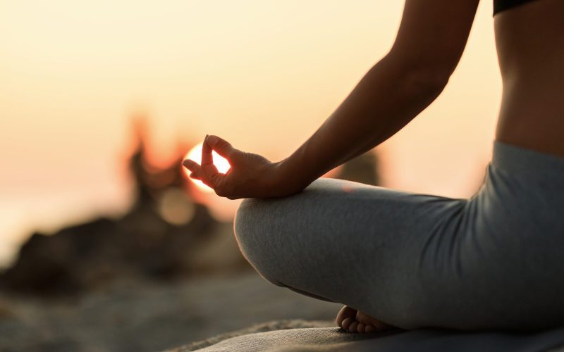 close-up-woman-meditating-lotus-position-sunset